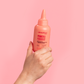 Hand holding a pink bottle of Lee Stafford Power Foods against a pink background