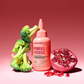 Lee Stafford Power Foods hair treatment bottle with broccoli and pomegranate on a red background