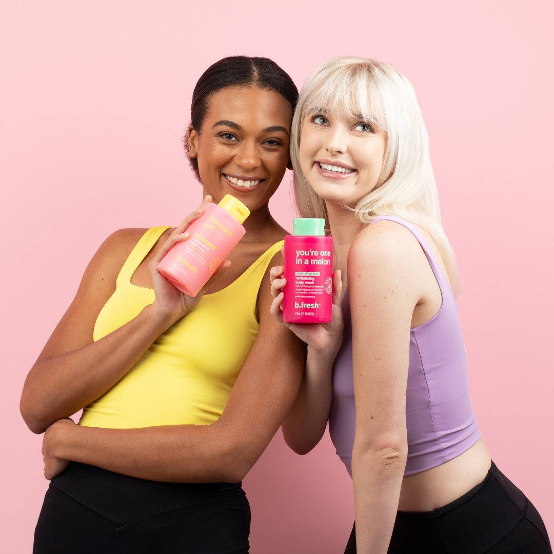 Two women holding pink bottles against a pink background